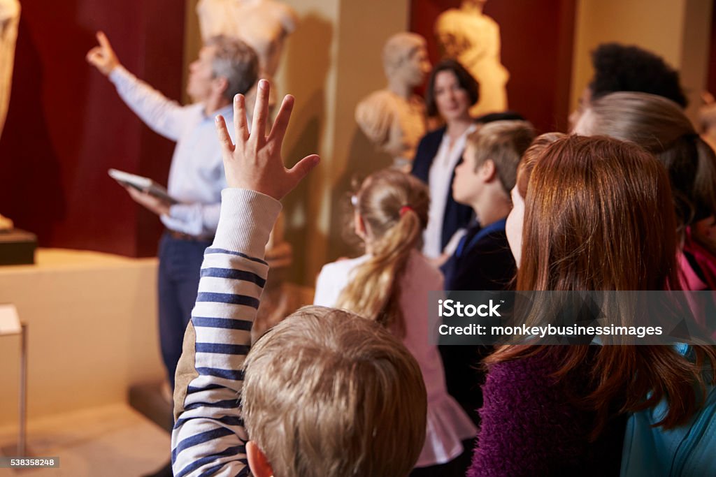 Pupils And Teacher On School Field Trip To Museum With Guide